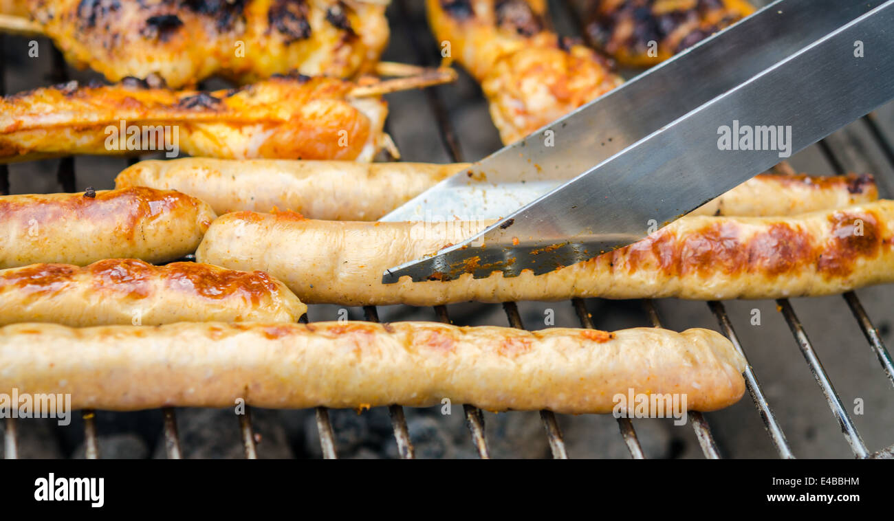 Saucisses et des ailes de poulet sur le barbecue grill fumeurs Banque D'Images