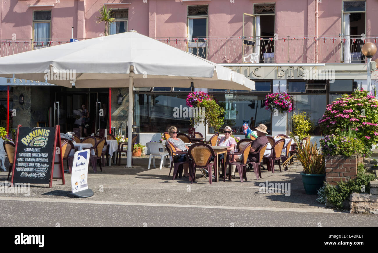 Les gens assis à l'extérieur d'un restaurant au bord de la mer, se détendre en été, England, UK Banque D'Images