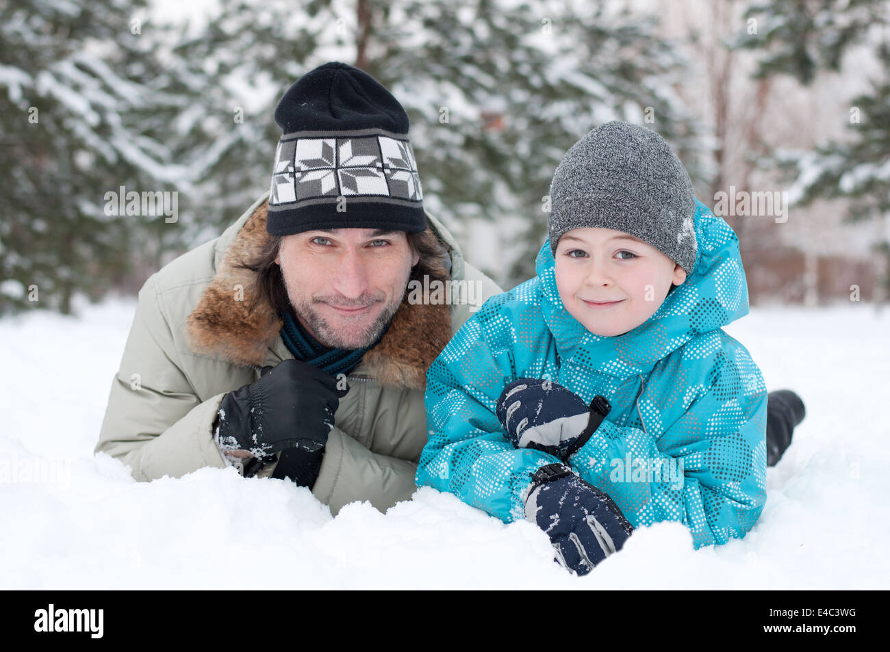 Famille son père, père de l'enfant de la neige deux vacances d'hiver forêt du parc à pied se trouvent des arbres Pin epicéa vêtements hat cap jacket light blue Banque D'Images