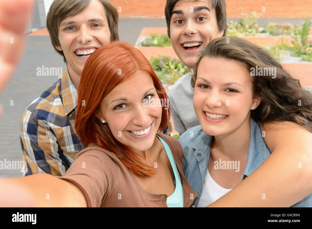 Groupe d'étudiants amis adolescents en tenant l'appareil photo de rire de selfies Banque D'Images