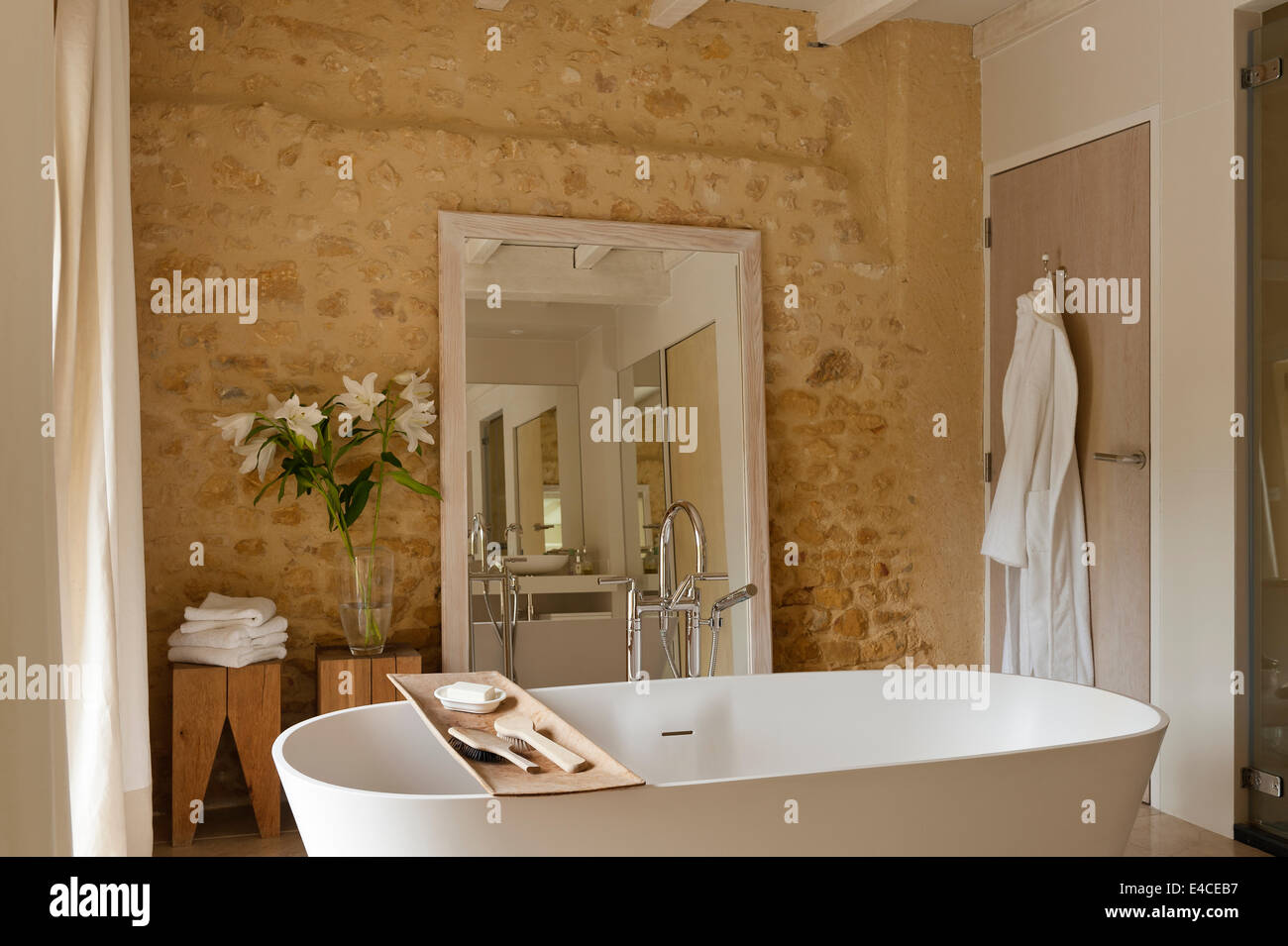 Une profonde baignoire 910 AV de l'agapè dans la salle de bains avec des murs en pierre et un grand miroir Banque D'Images