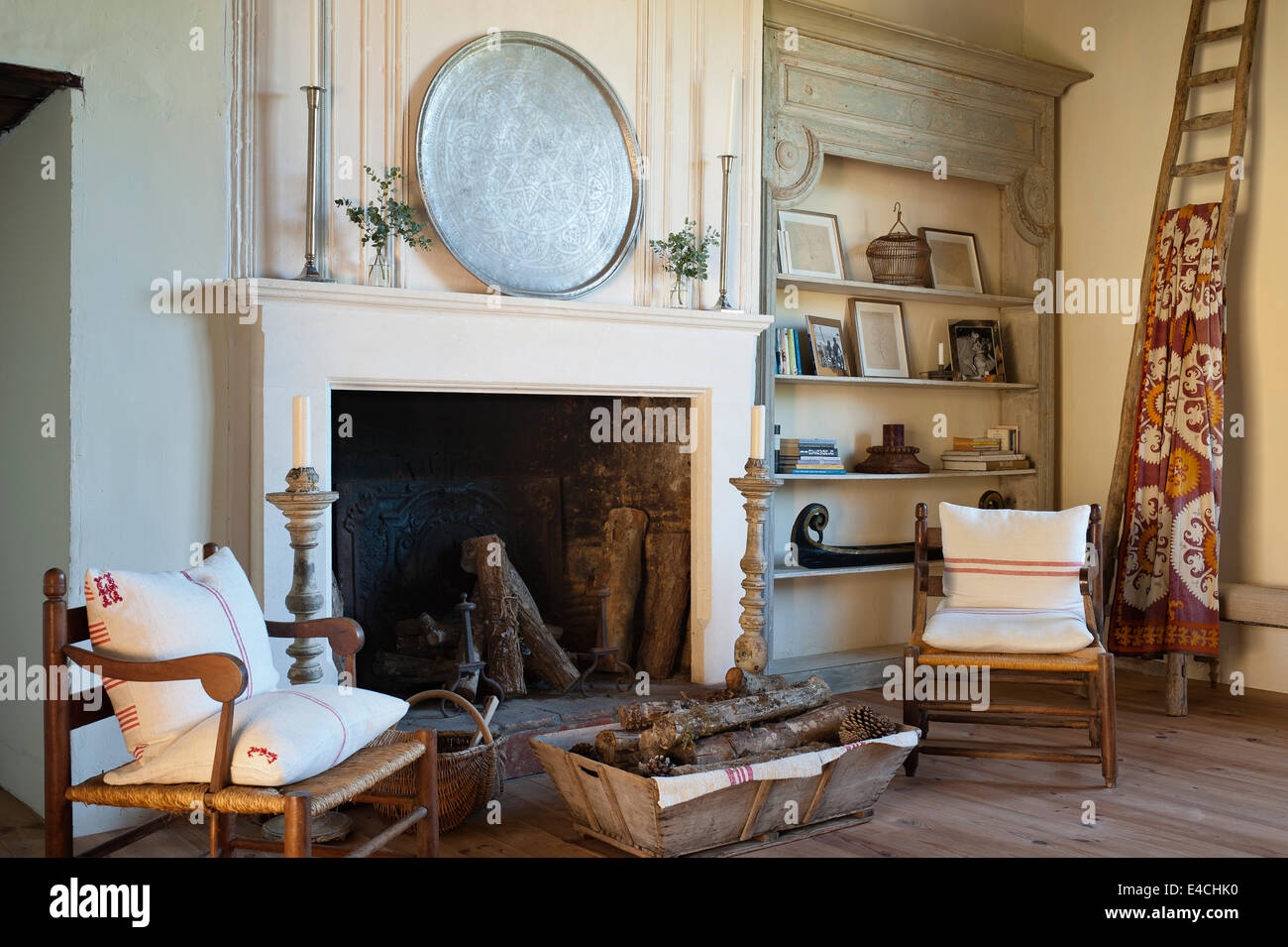 Fauteuils en bois et se connecter panier par une grande cheminée dans le salon spacieux. Une antique pend textile à partir d'un vieux de la Banque D'Images