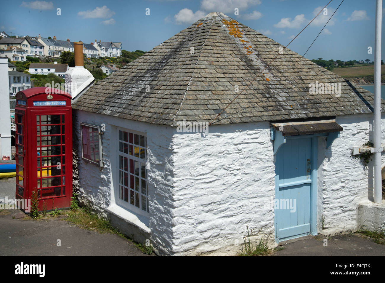 Cornwall. La péninsule de Roseland. Portscatho.téléphone rouge boîte à côté de cottage blanchis Banque D'Images
