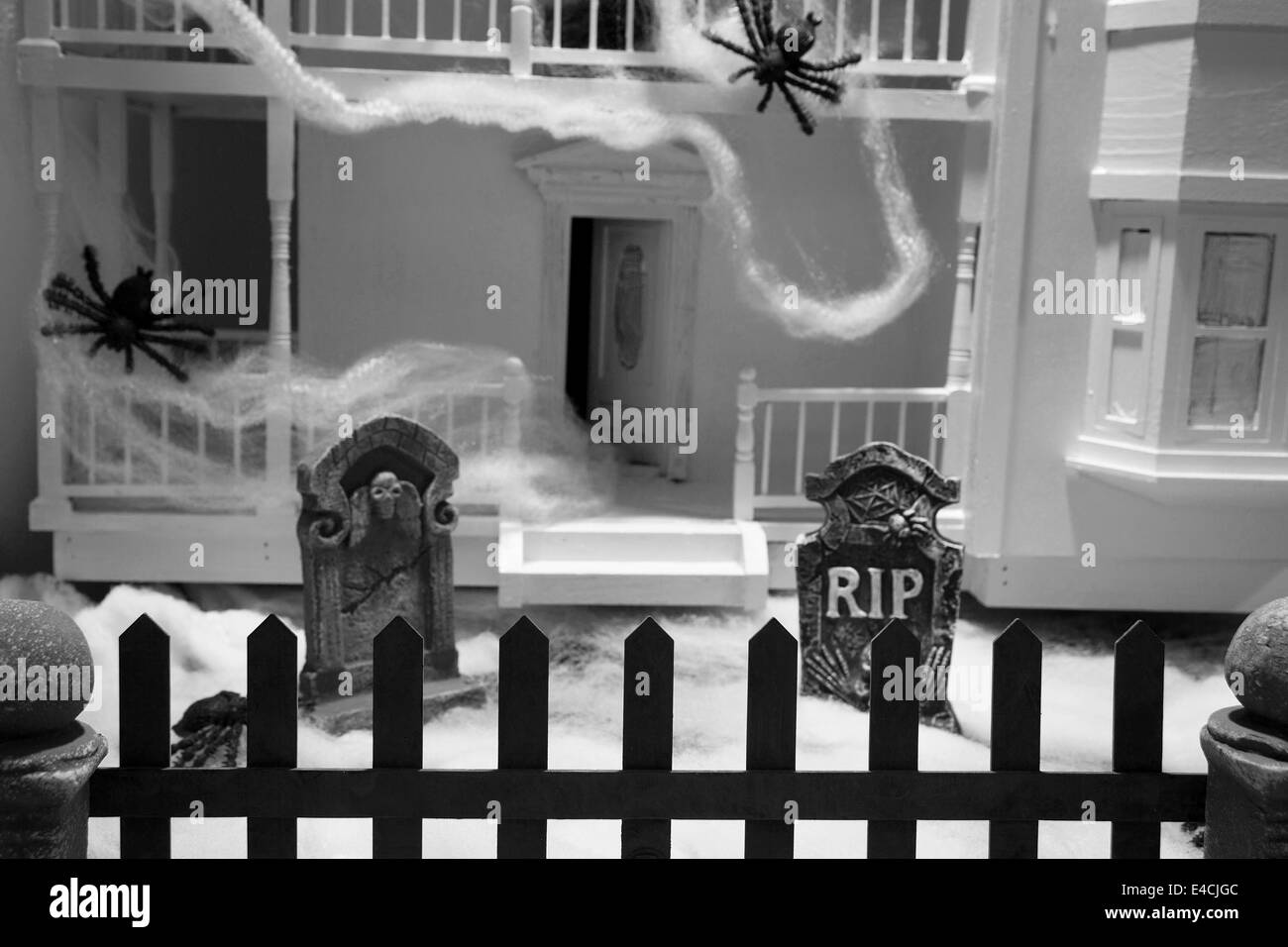 Maison en décomposition décoré de toiles d'araignée et des araignées avec des pierres tombales dans la cour avant. Banque D'Images