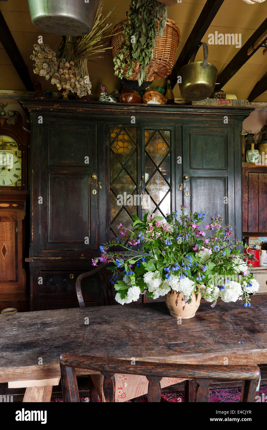 Vase de fleurs sur table en bois étroit en pays cuisine avec ancien cabinet Banque D'Images