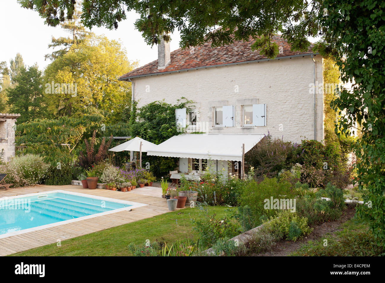 Piscine extérieure dans le jardin d'une ancienne usine française avec auvent, pelouse et fleurs Banque D'Images