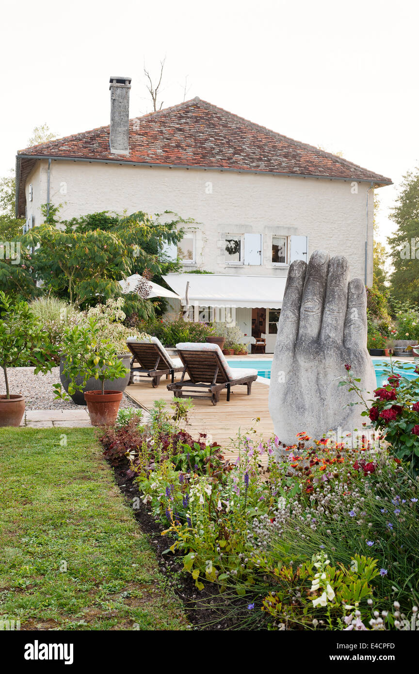 La main de pierre dans la sculpture française de jardin ancien moulin rénové avec piscine extérieure et terrasse en bois Banque D'Images