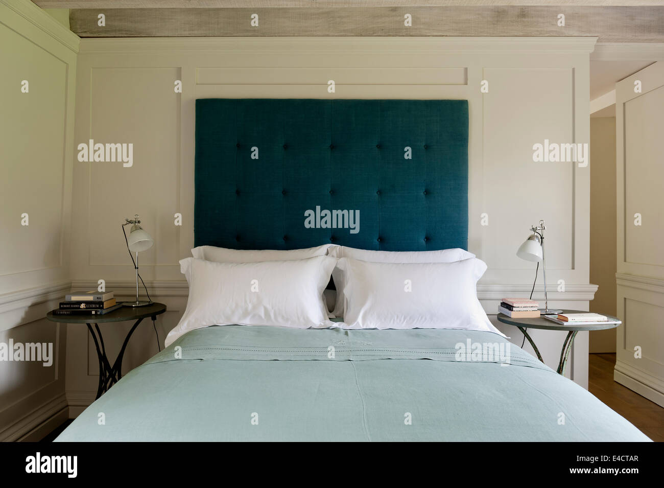 Tête de lit boutonnées sur le lit dans la chambre avec lambris blanc et des tables de chevet circulaire Banque D'Images