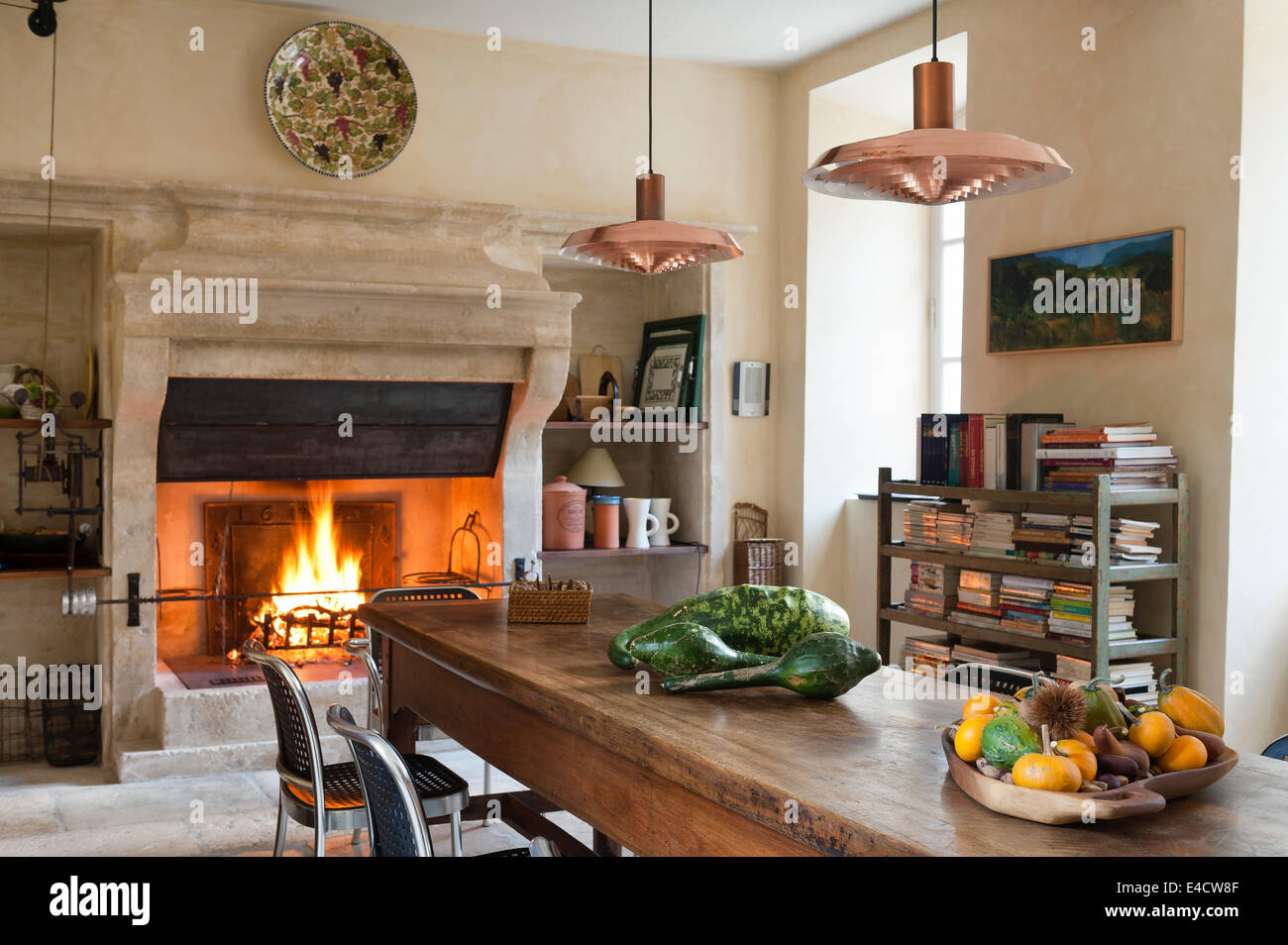 La cuisine provençale avec grande cheminée en pierre et table à manger en bois. La poignée de cuivre sont d'un design Arne Jacobsen Banque D'Images