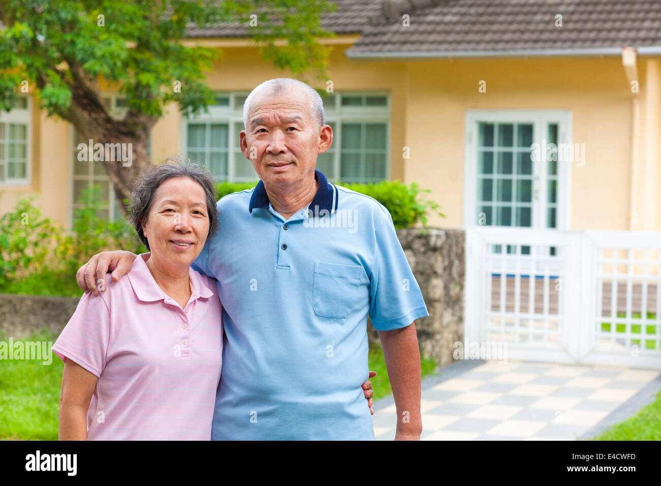 Happy asian senior couple standing in front of a house Banque D'Images