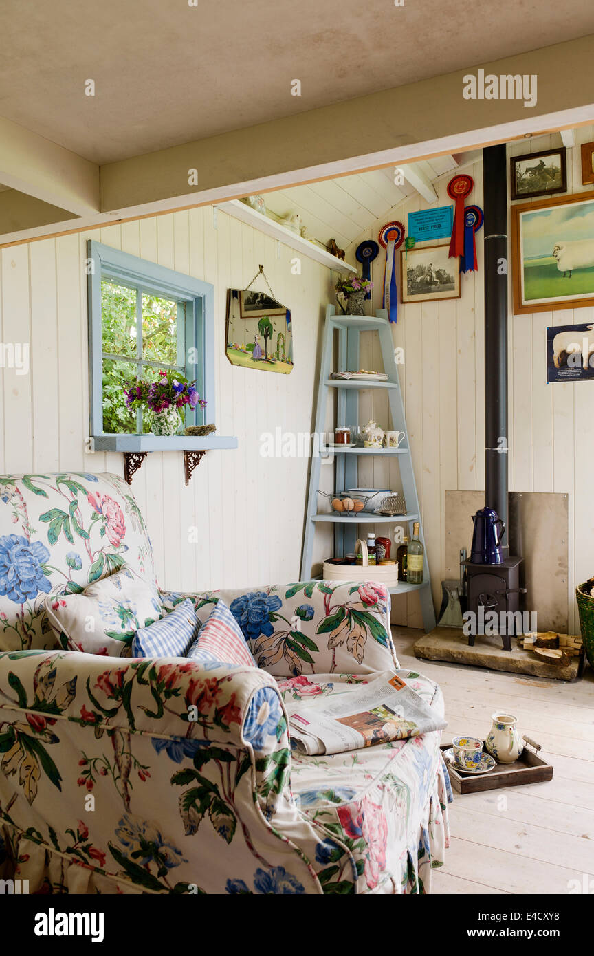 Un fauteuil à motifs floraux dans une cabane de bergers avec un 'Wendy' poêle à bois par temps venteux Smithy Banque D'Images