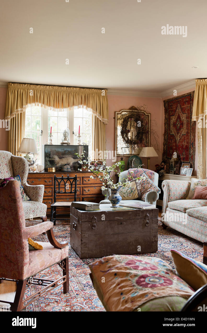 Canapés rembourrés floral et chaises à aile en salle de dessin avec de vieux coffres, un assortiment de textiles et de verre taxidermie tubé Banque D'Images