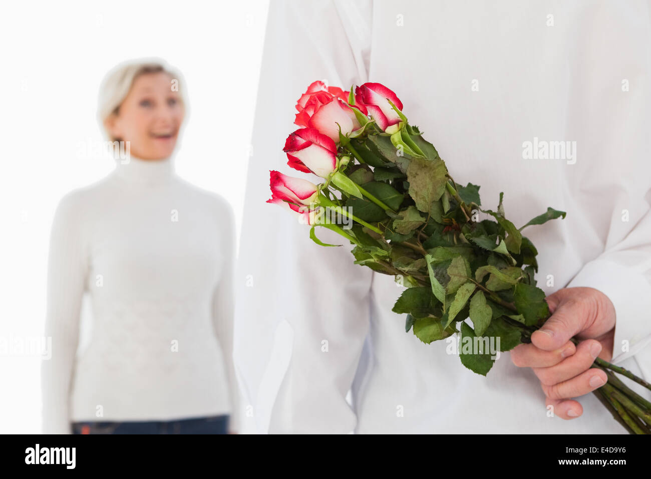 Man hiding bouquet de roses à partir de la femme plus âgée Banque D'Images