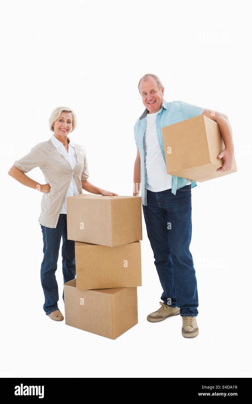 Older couple smiling at camera with moving boxes Banque D'Images