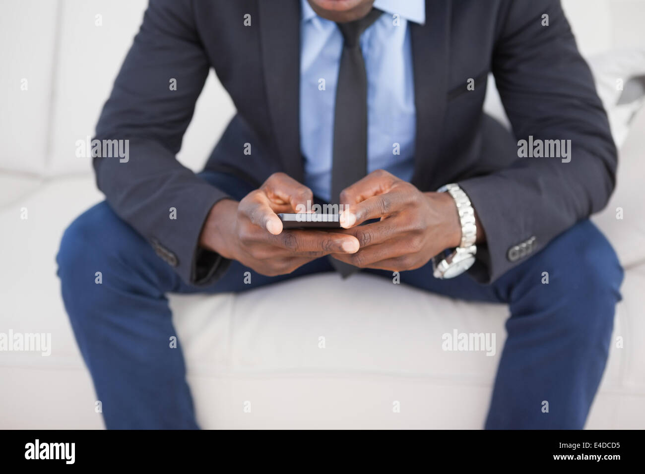 Businessman texting on phone on sofa Banque D'Images