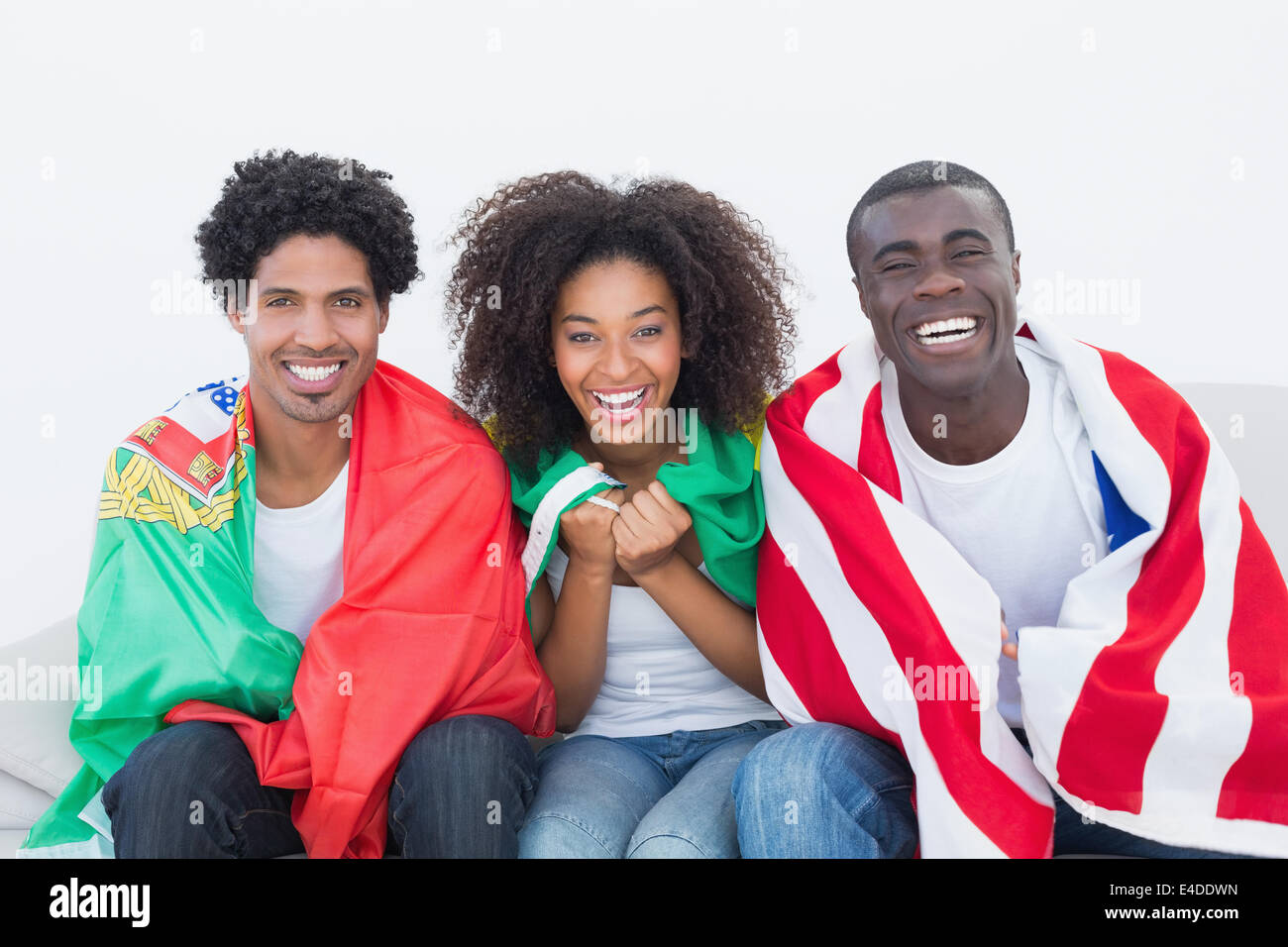 Les fans de football sitting on couch with flags Banque D'Images