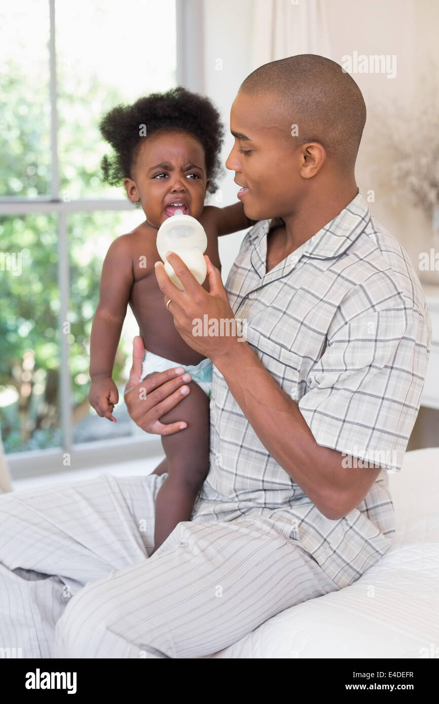 Heureux père essayer de nourrir son bébé fille grincheux Banque D'Images