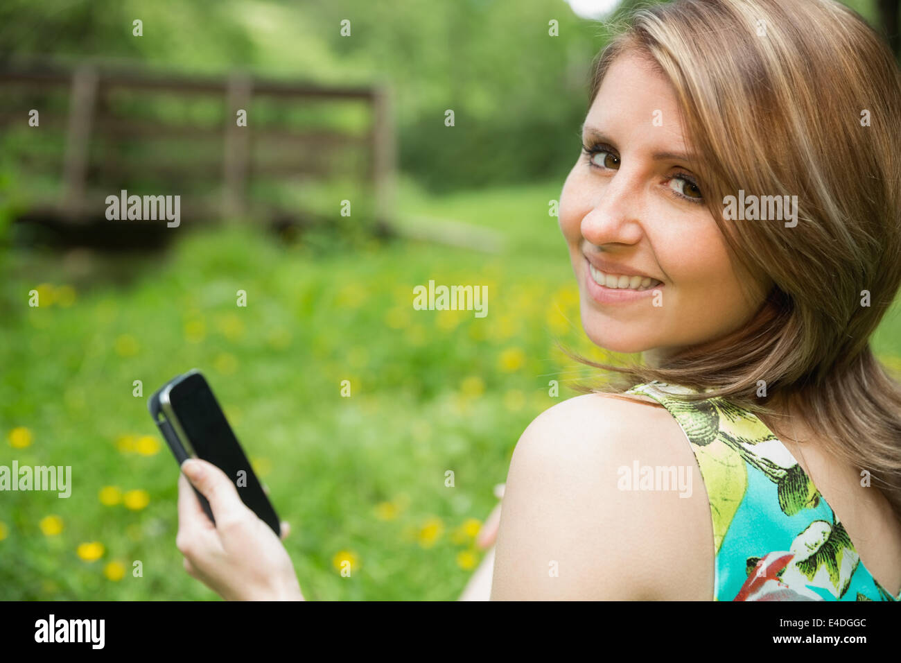 Smiling woman text messaging in field Banque D'Images
