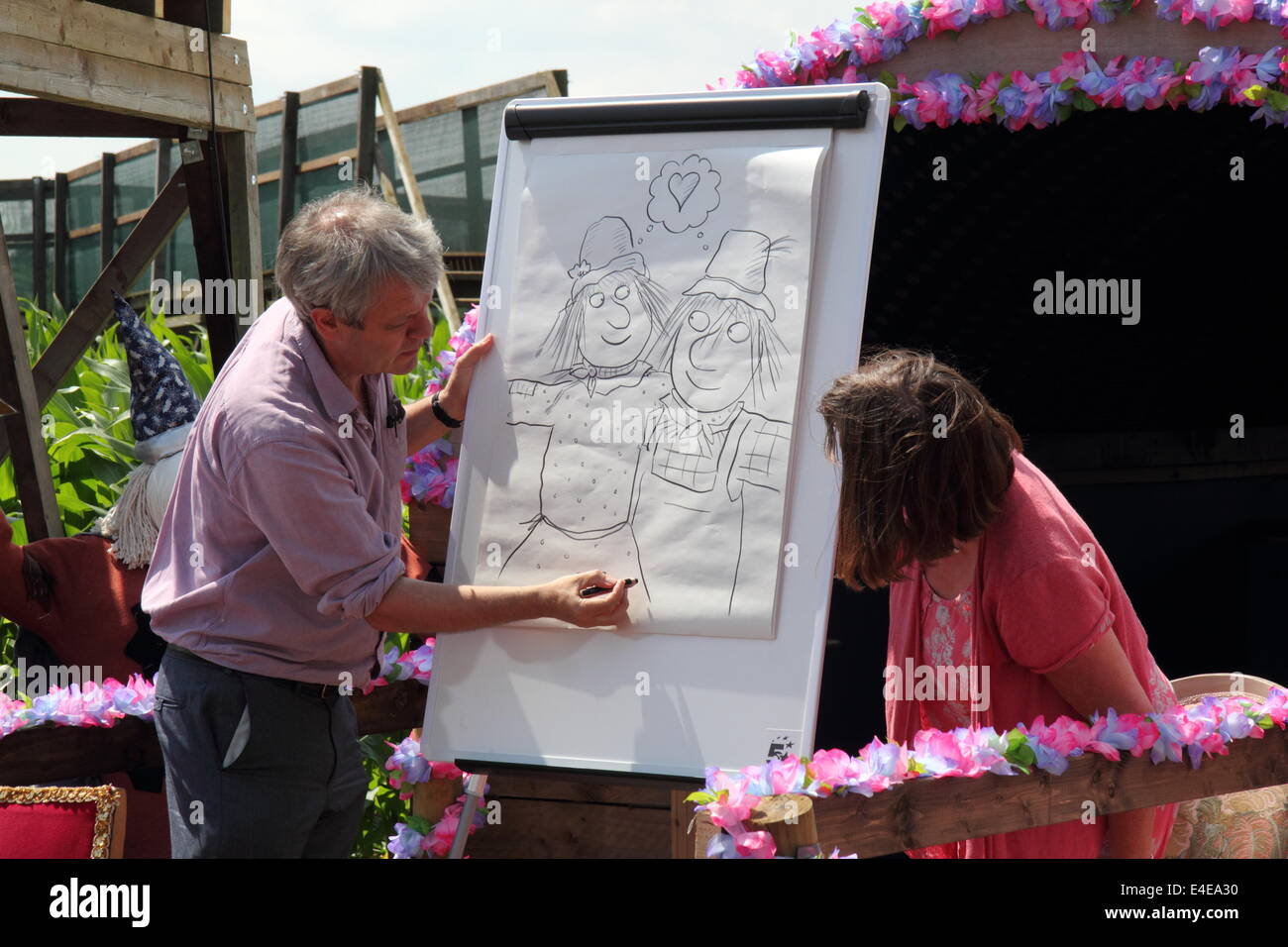 Burton-on-Trent, Staffordshire, Royaume-Uni. 09 juillet 2014. Axel Scheffler dessine les personnages de l'épouvantails' Wedding regardé par l'auteur, Julia Donaldson.L'Aventure en forêt National Farm lance sa 11e édition annuelle de maïs de 4 hectares labyrinthe qui, cette année, célèbre la publication de Les épouvantails' livre de mariage par les créateurs de The Gruffalo & Stick Man). Conçu dans la forme des épouvantails' caractères Mariage Betty O'Orge et Harry O'Hay, le labyrinthe dispose de trois kilomètres de voies, ponts et affichage des tours. Credit : Deborah Vernon/Alamy Live News Banque D'Images