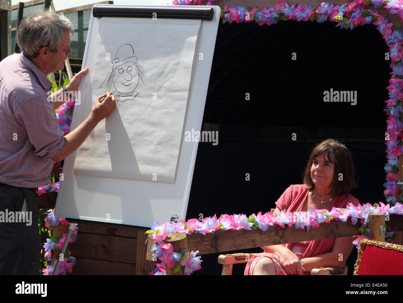 Burton-on-Trent, Staffordshire, Royaume-Uni. 09 juillet 2014. Axel Scheffler dessine les personnages de l'épouvantails' Wedding regardé par l'auteur, Julia Donaldson.L'Aventure en forêt National Farm lance sa 11e édition annuelle de maïs de 4 hectares labyrinthe qui, cette année, célèbre la publication de Les épouvantails' livre de mariage par les créateurs de The Gruffalo & Stick Man). Conçu dans la forme des épouvantails' caractères Mariage Betty O'Orge et Harry O'Hay, le labyrinthe dispose de trois kilomètres de voies, ponts et affichage des tours. C'est le premier livre que l'auteur, Julia Donaldson MBE et Illustrator, Axel Scheffler hav Banque D'Images