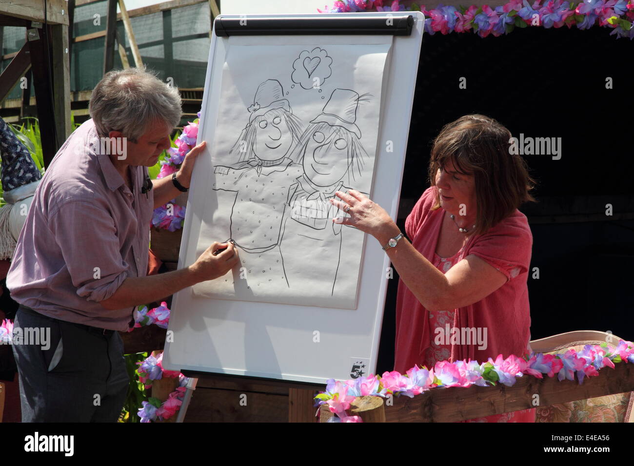 Burton-on-Trent, Staffordshire, Royaume-Uni. 09 juillet 2014. Axel Scheffler dessine les personnages de l'épouvantails' Wedding regardé par l'auteur, Julia Donaldson.L'Aventure en forêt National Farm lance sa 11e édition annuelle de maïs de 4 hectares labyrinthe qui, cette année, célèbre la publication de Les épouvantails' livre de mariage par les créateurs de The Gruffalo & Stick Man). Conçu dans la forme des épouvantails' caractères Mariage Betty O'Orge et Harry O'Hay, le labyrinthe dispose de trois kilomètres de voies, ponts et affichage des tours. Credit : Deborah Vernon/Alamy Live News Banque D'Images