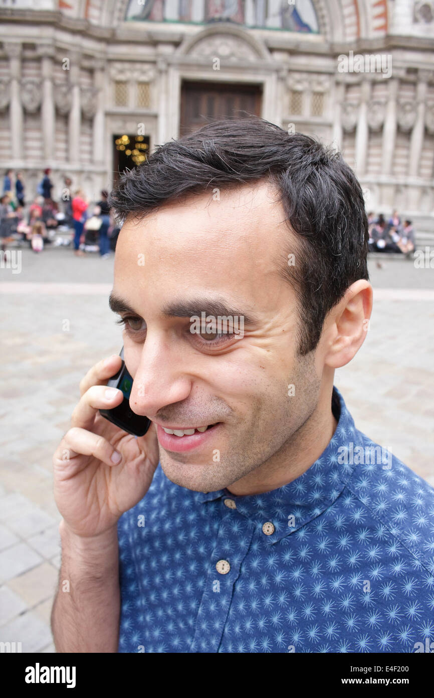 Un homme de la Méditerranée en conversation sur son téléphone intelligent dans une plaza Banque D'Images