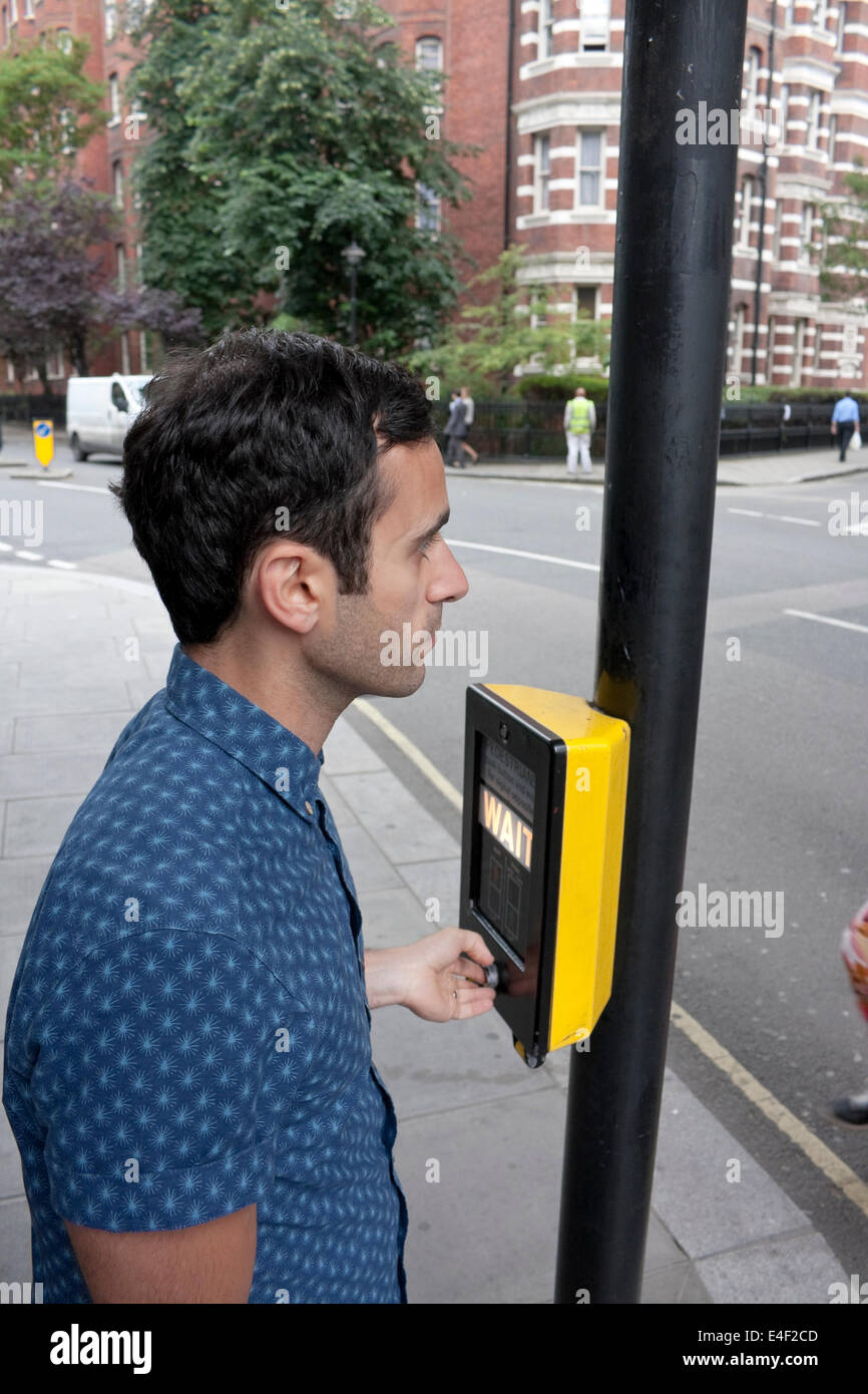 Un homme à l'aide d'un passage piéton pour traverser la route d'attente Banque D'Images