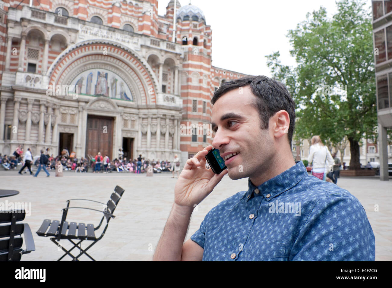 Un homme de la Méditerranée en conversation sur son téléphone intelligent assis dehors dans une plaza Banque D'Images