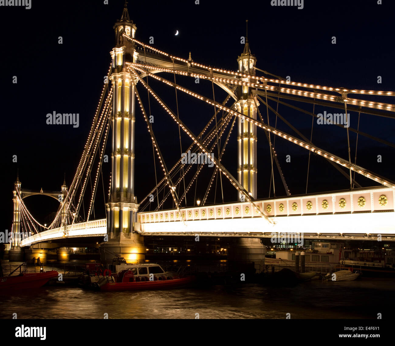 Cette image montre Albert Bridge à Londres, en Angleterre avec un quartier de lune dans l'arrière-plan. Banque D'Images