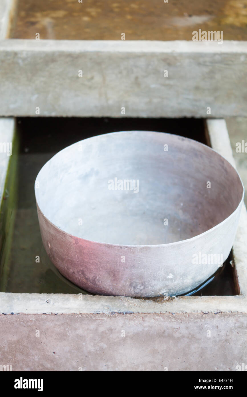 Ancien bol à eau en acier inoxydable unique flottant sur l'eau Banque D'Images