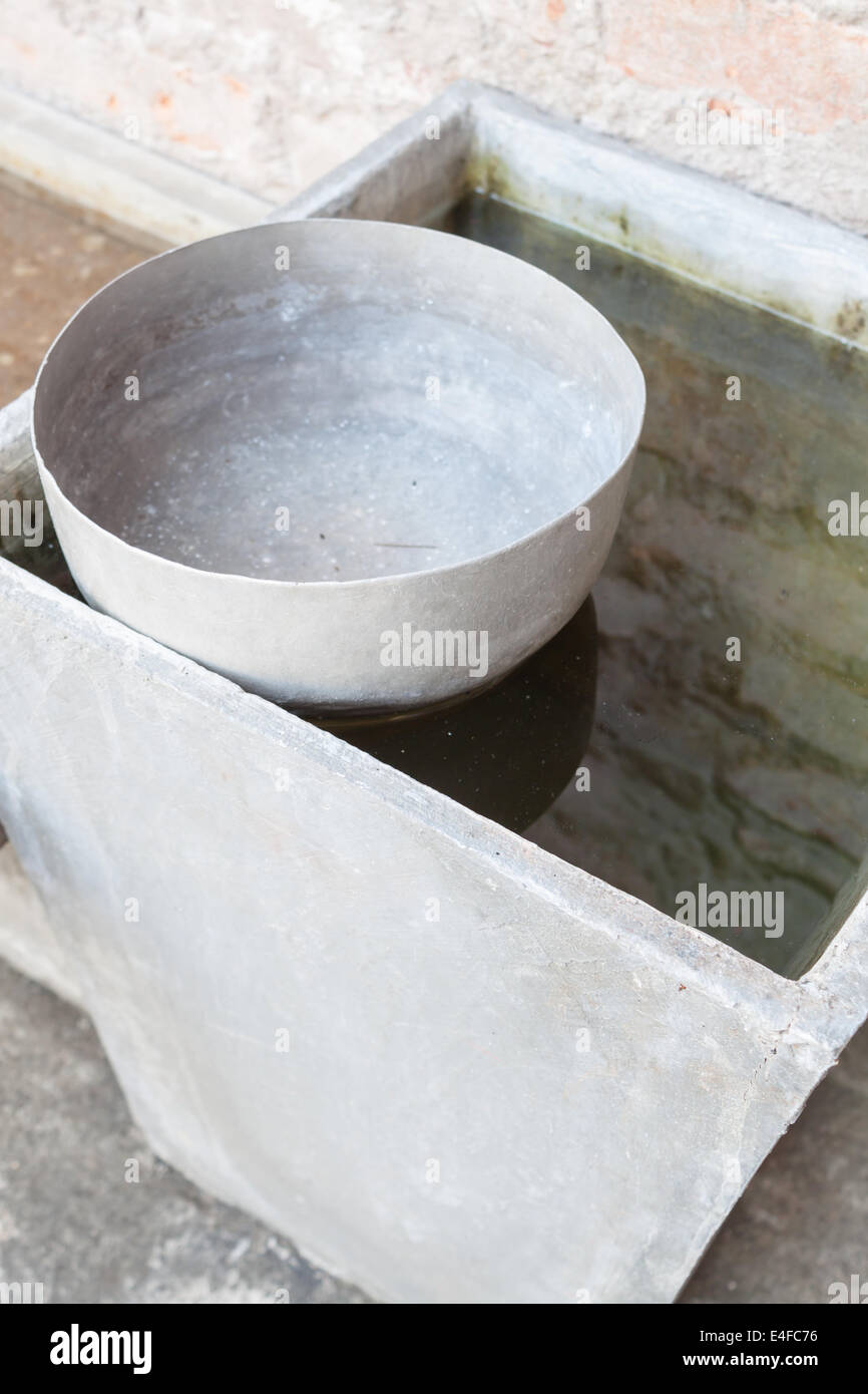 Ancien bol à eau en acier inoxydable unique entouré par l'eau Banque D'Images