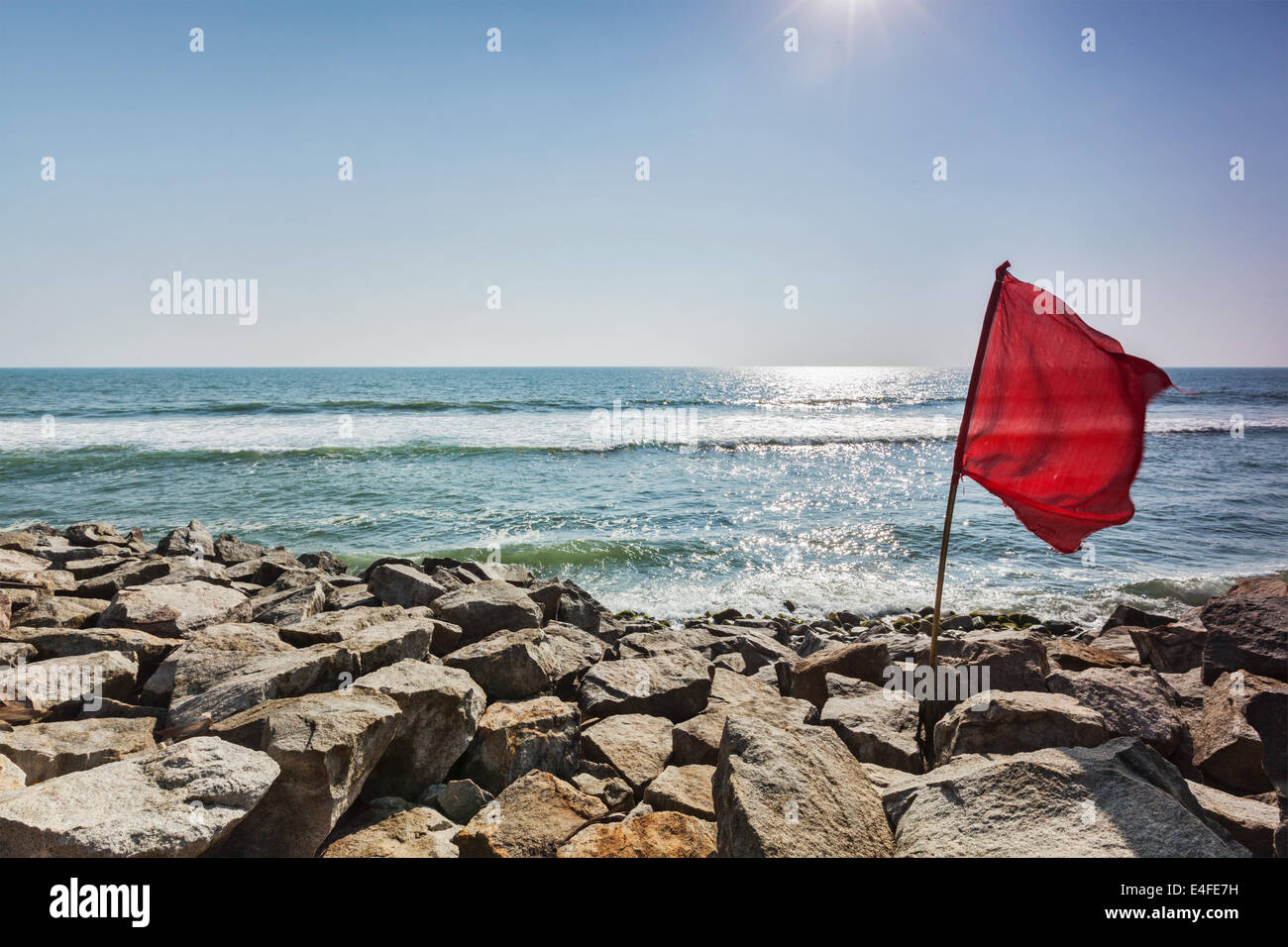 Danger - drapeau rouge sur plage rocheuse interdisant à nager Banque D'Images