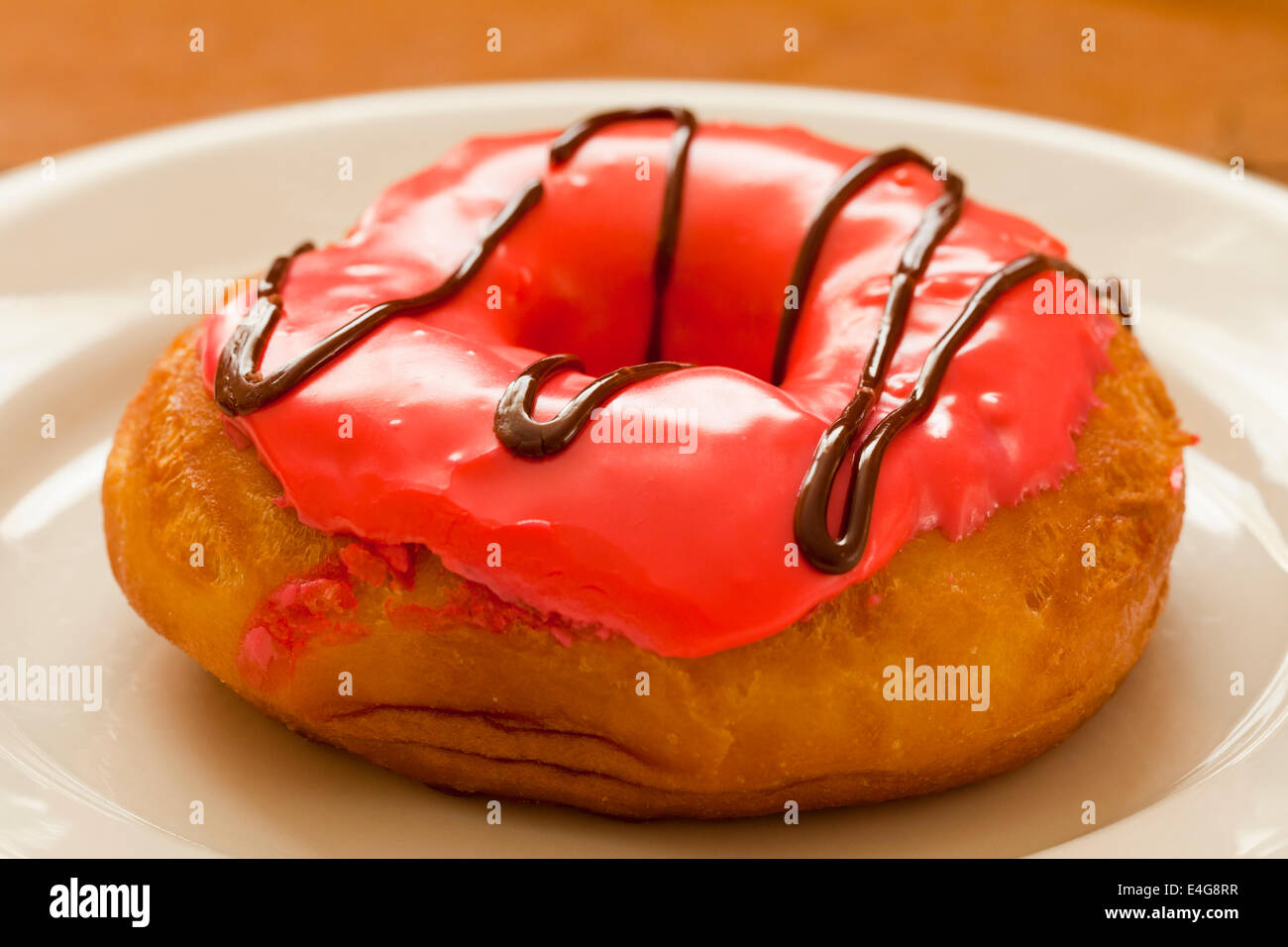 Strawberry frosted doughnut on plate Banque D'Images