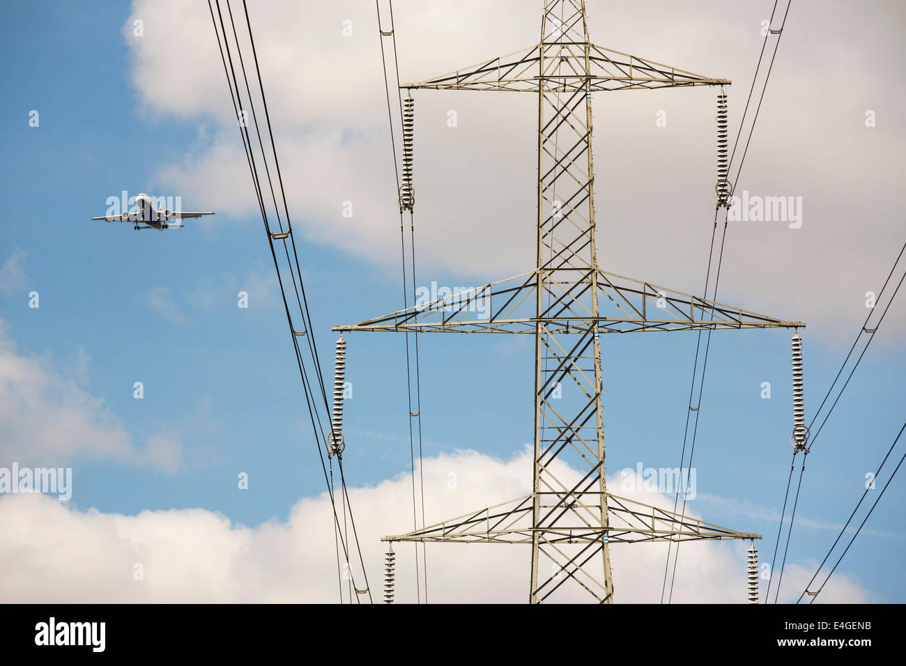 Un avion voler au-delà d'un pylône d'électricité comme il arrive en terre à City airport, London, UK. Banque D'Images