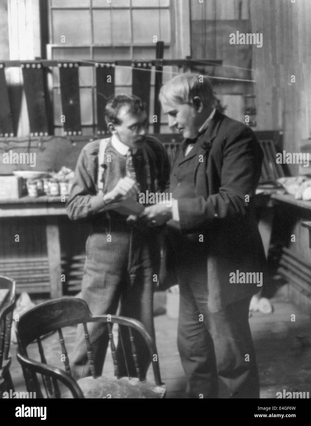 Thomas Alva Edison, debout dans son laboratoire, discuter d'un problème avec un ouvrier, vers 1906 Banque D'Images
