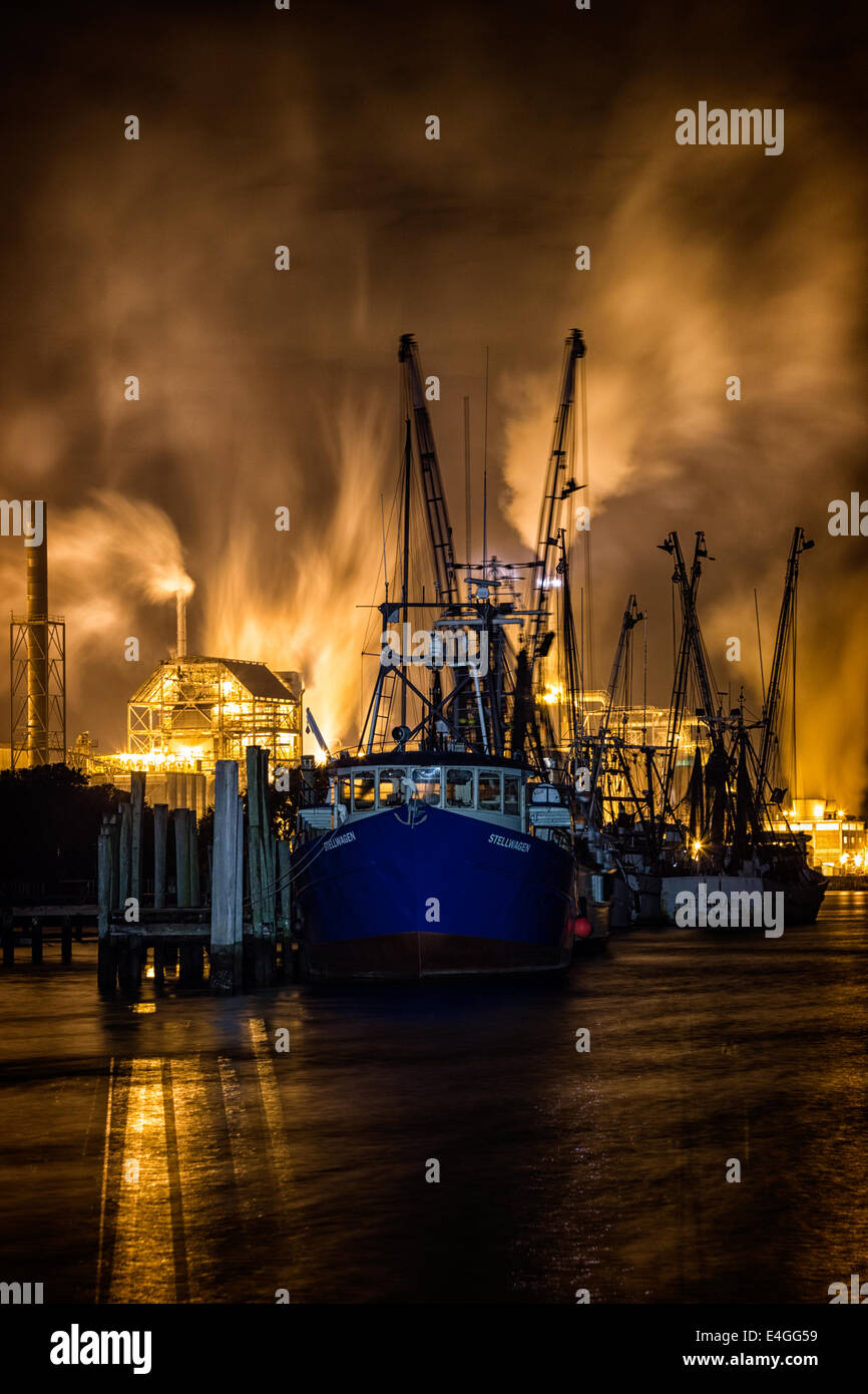 Photographie de nuit spectaculaire Fernandina Beach crevettiers, éclairé par les lumières de l'usine de pâte Rayonier sur Amelia Island. Banque D'Images