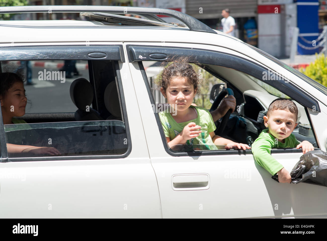 Ramallah. 10 juillet, 2014. Deux jeunes enfants palestiniens regarde par la fenêtre d'une voiture qui passait dans le centre commercial de la place Al-Manara. Les manifestations ont été éclatent dans la région en réaction au récent conflit avec Israël. Kevin Su/Alamy Live News Banque D'Images