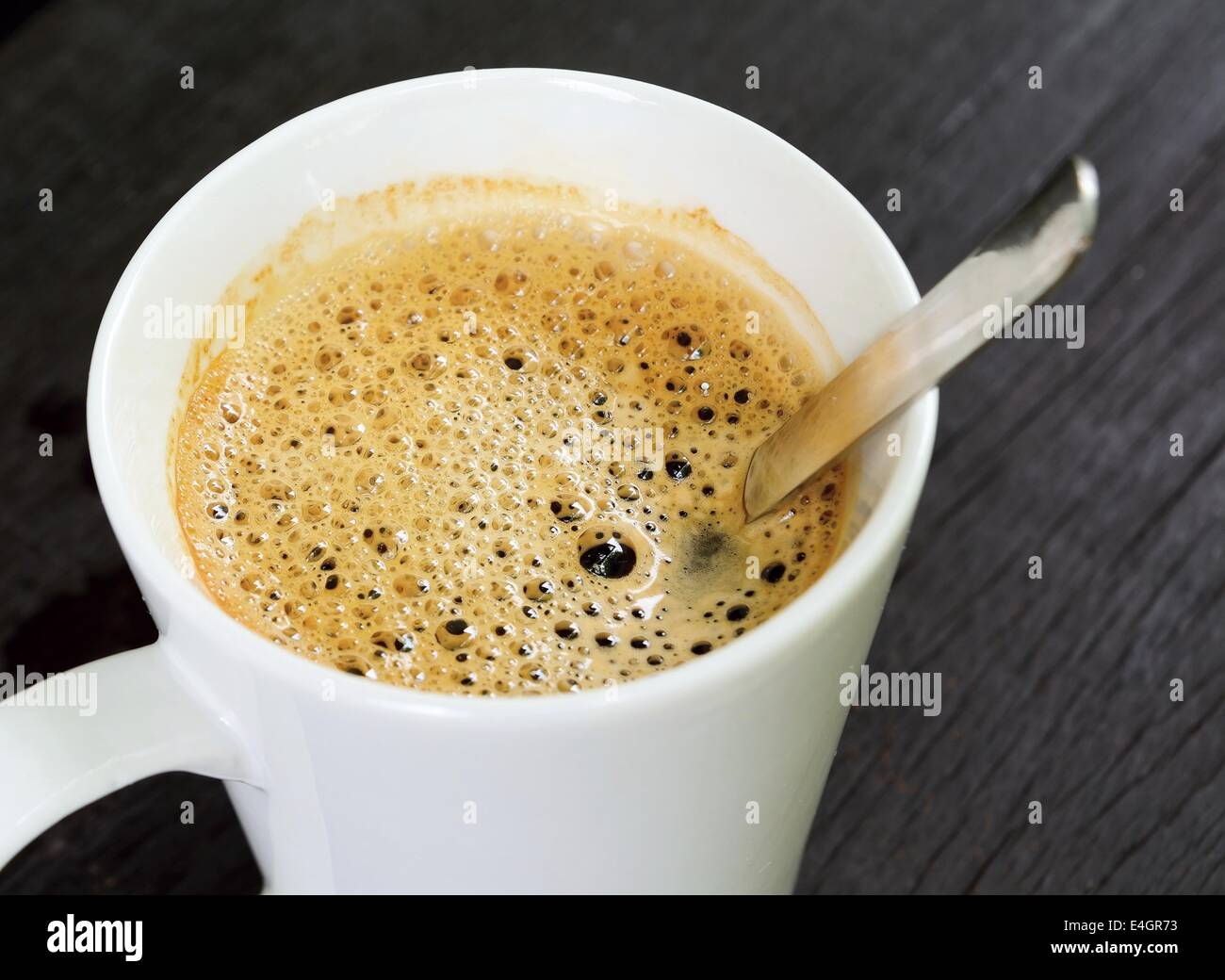 Vue de dessus de la tasse de café brun avec blanc et la cuillère sur la table en bois brun. Banque D'Images