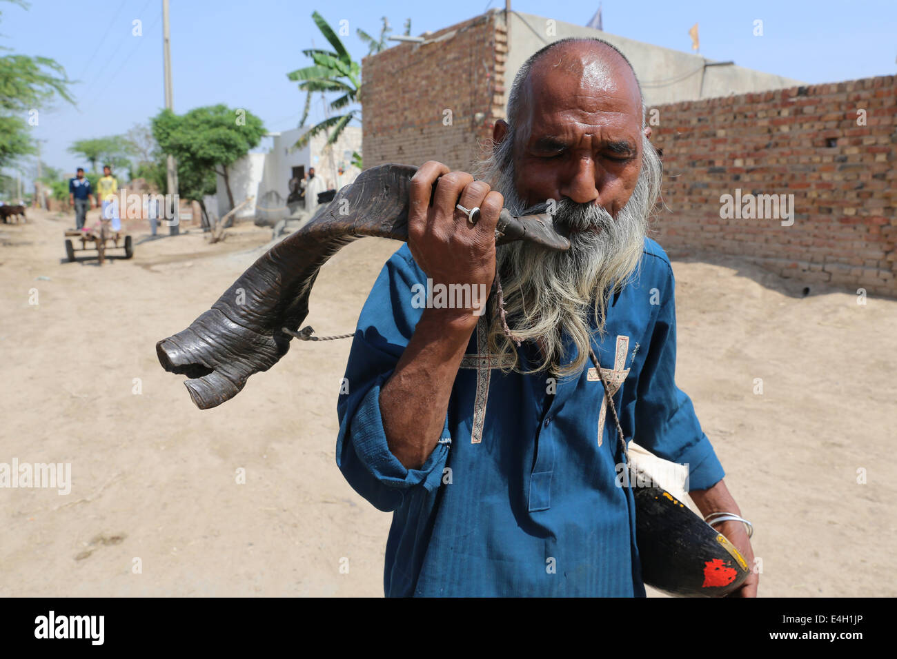 L'homme souffle sur une corne de chèvre, Khushpur village, Punjab, Pakistan Banque D'Images