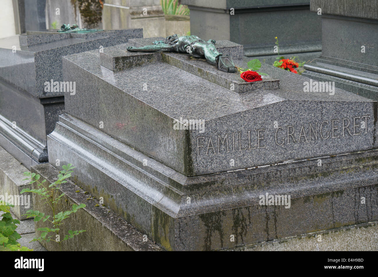 Une rose rouge sur une pierre tombale en granit dans le cimetière du Père Lachaise Paris dans la pluie d'été Banque D'Images