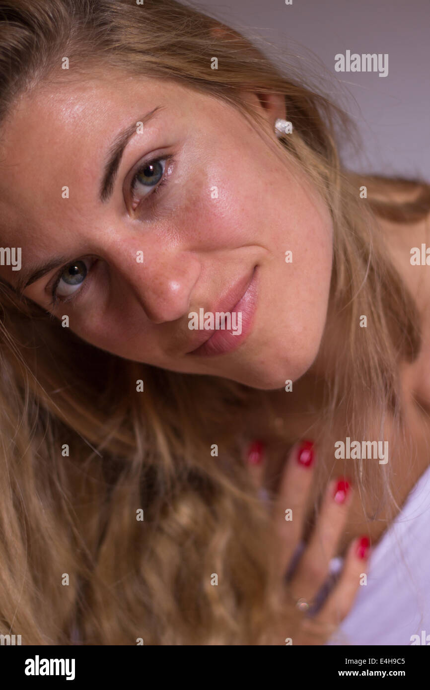 Jeune femme belle face closeup portrait 'toucher' visage souriant à l'intérieur 'looking at camera' Banque D'Images