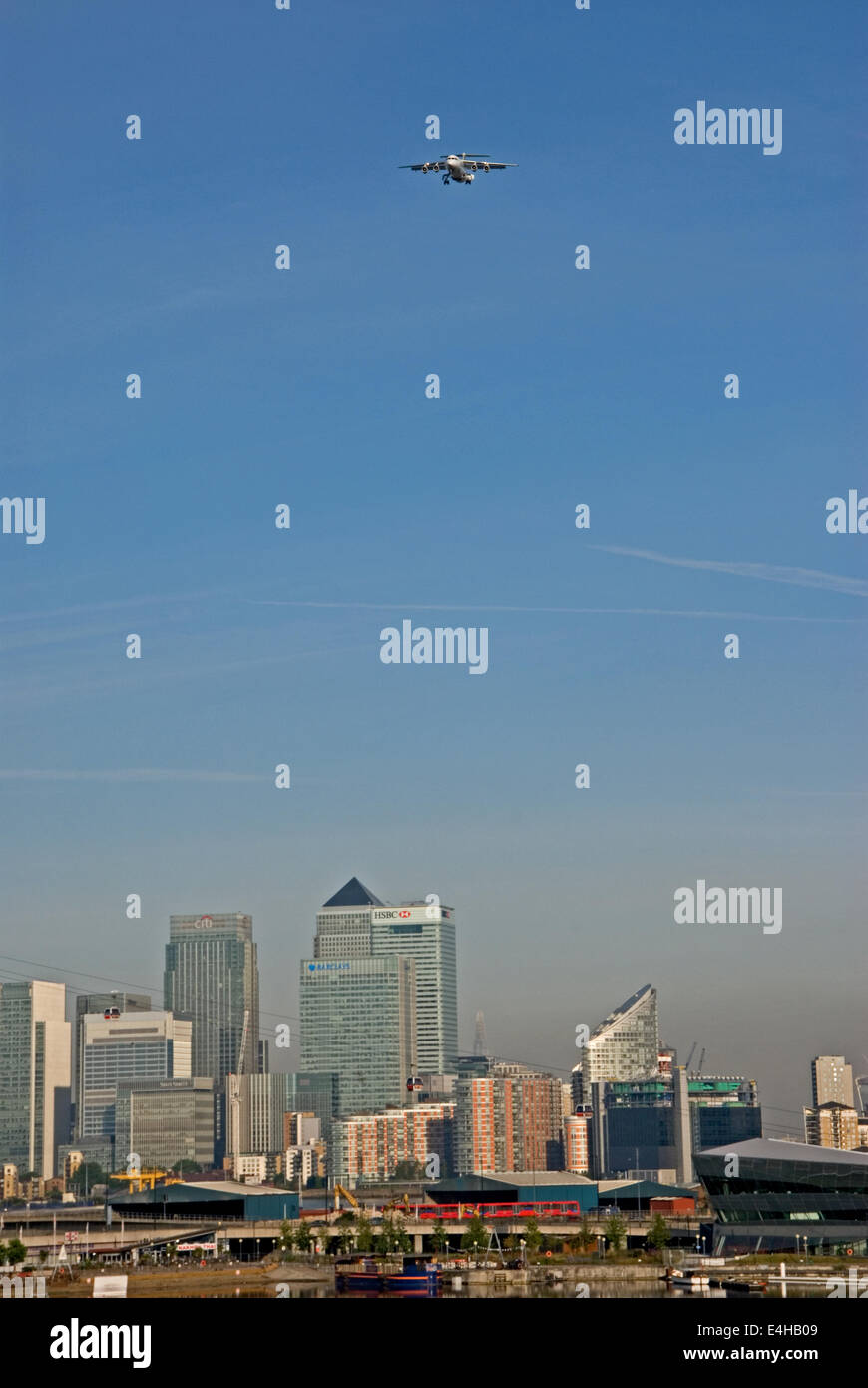 Un avion en direction de l'aéroport de London City passe sur les gratte-ciel du Canary Wharf à l'Est de Londres, avec la pollution de l'air visible dans le ciel Banque D'Images