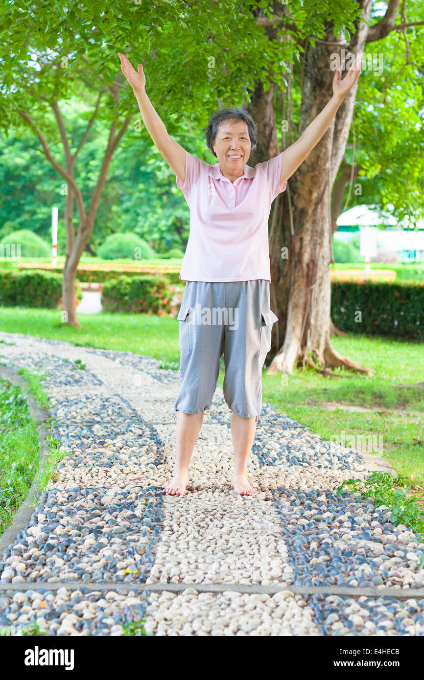 Heureux grand-mère debout sur la passerelle de pierre et élever les mains Banque D'Images