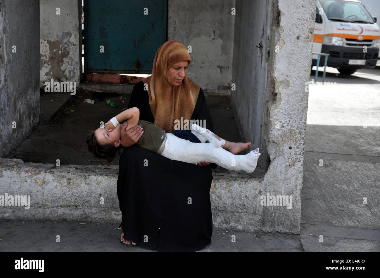 La ville de Gaza, bande de Gaza, territoire palestinien. 12 juillet, 2014. Une femme palestinienne porte son fils habitué à la suite d'une frappe aérienne israélienne à al-l'hôpital Shifa à Gaza City, . Credit : ZUMA Press, Inc./Alamy Live News Banque D'Images