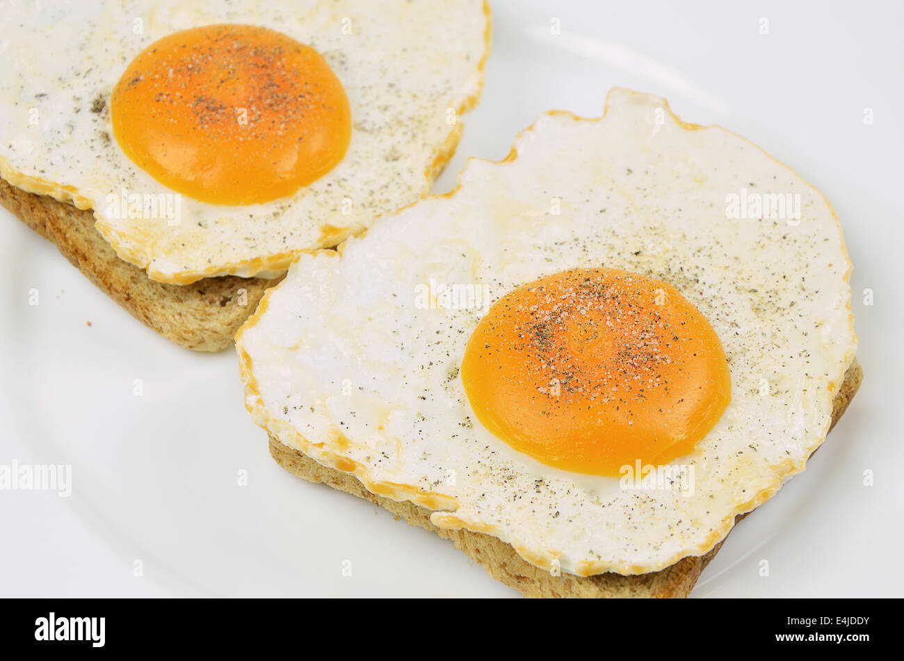 Deux oeufs au plat avec du sel et du poivre sur toast, Close up on white plate, full frame Banque D'Images