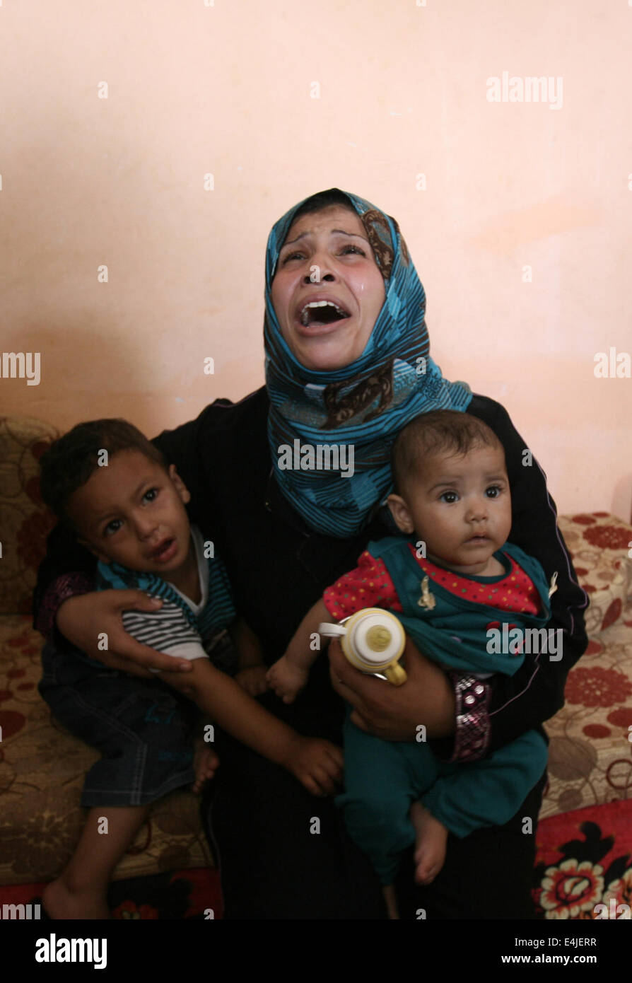 Khan Younis, dans la bande de Gaza, territoire palestinien. Le 13 juillet, 2014. Parents pleurer la mort de 3 ans garçon Moayad palestinienne al-Araj, qui selon les responsables de l'hôpital ont été tués dans une frappe aérienne israélienne, lors de ses funérailles à Khan Younis dans le sud de la bande de Gaza, le 13 juillet 2014. La grève a été la plus meurtrière dans la ville de Gaza juste avant minuit (2100 GMT) dans l'est du district de Touffah où 18 personnes ont été tuées dans des grèves qui a frappé la maison de chef de la police du Hamas Tayseer al-Batsh et une mosquée, medecins dit Crédit : Eyad Al Baba/APA/Images/fil ZUMA Alamy Live News Banque D'Images