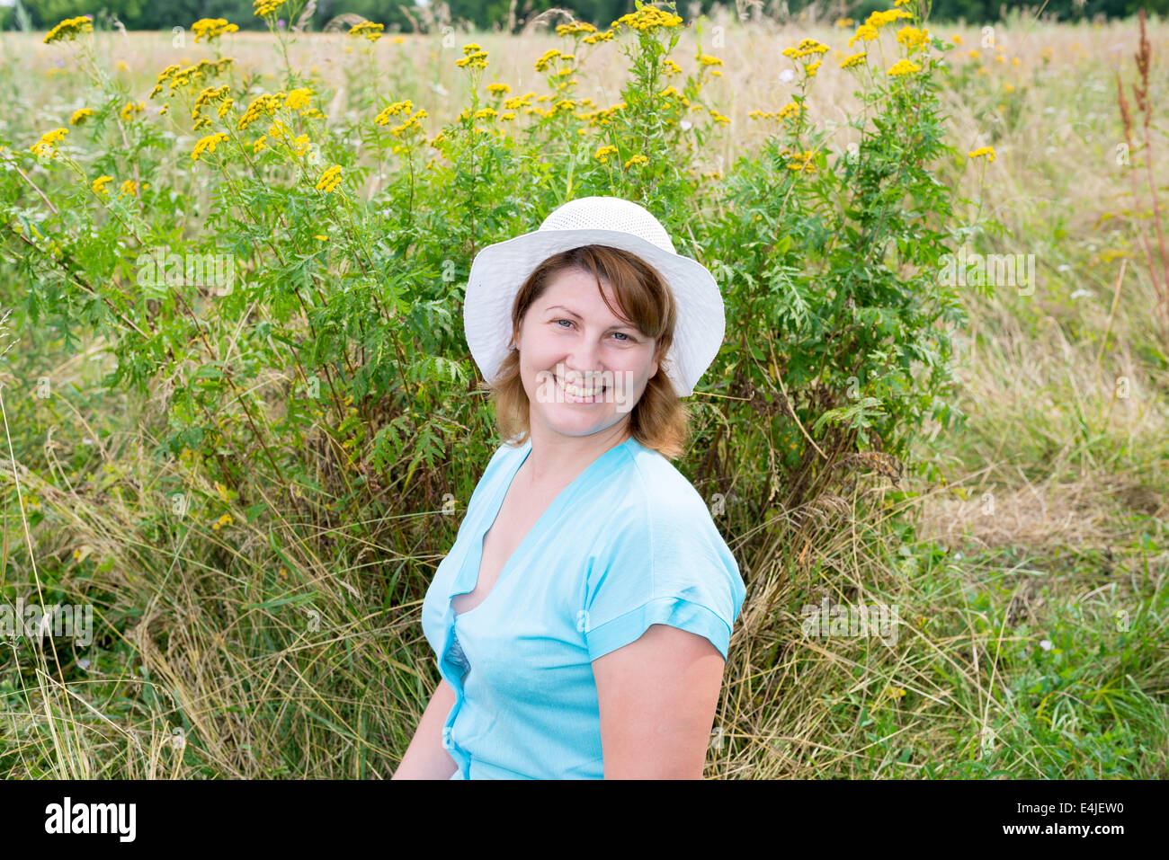 Femme d'âge moyen sur une prairie avec tansy Banque D'Images