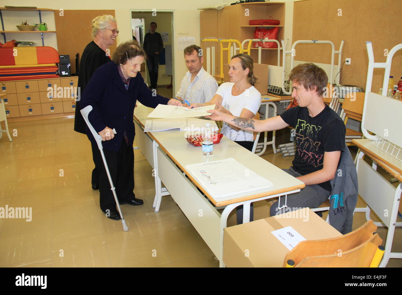 Ljubljana, Slovénie. Le 13 juillet, 2014. Une femme prend un formulaire de vote d'un membre du personnel à un bureau de scrutin établi dans la région de Ljubljana, capitale de la Slovénie, le 13 juillet 2014. Les Slovènes se sont rendus aux urnes le dimanche de la huitième élection générale du pays puisqu'il a rédigé une constitution en 1990. Plus de 1,7 millions d'électeurs sont tenus de voter, le choix de 90 députés à l'Assemblée nationale de plus de 1 100 candidats présentés par 17 parties. Credit : Zhao Yi/Xinhua/Alamy Live News Banque D'Images