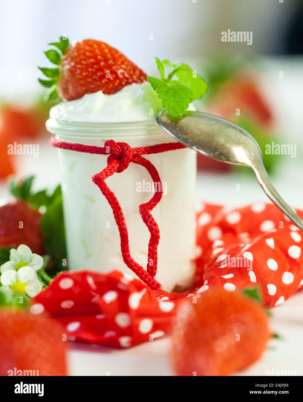 La ferme rouge frais mûrs fraises avec un bocal en verre de yaourt sain servi sur un pays rouge à pois pour une serviette deli Banque D'Images