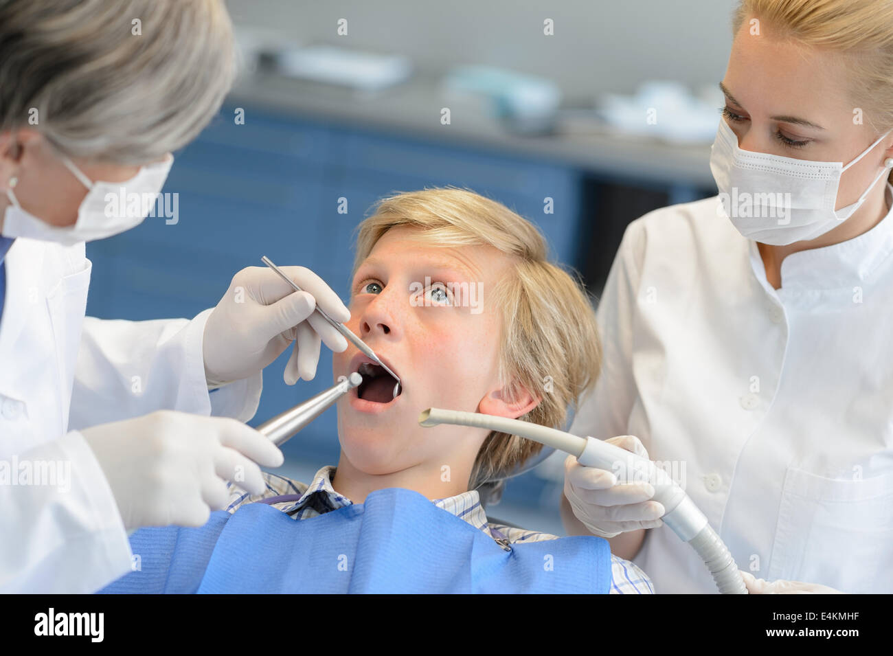 Dentiste et assistant avec peur teenage patient ouvert bouche checkup Banque D'Images